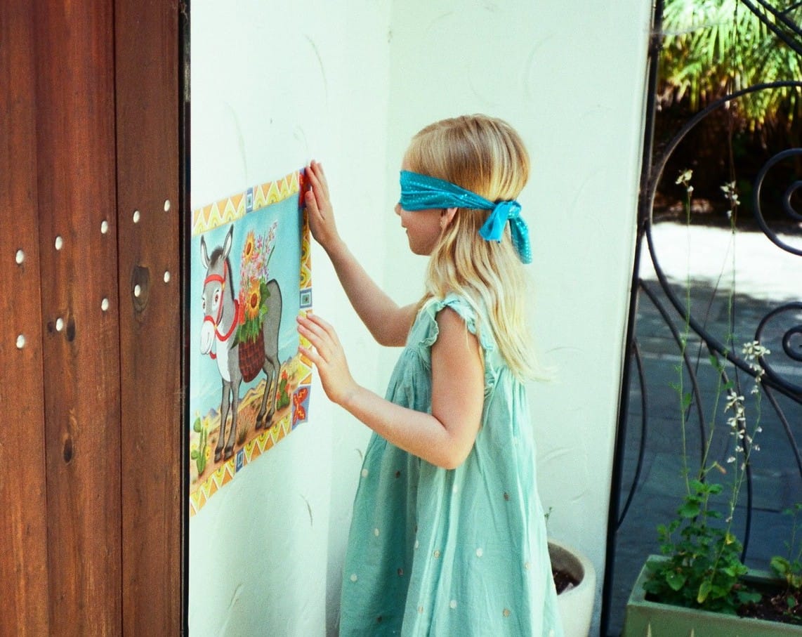 A young girl blindfolded, playing Pin the Tail on the Donkey